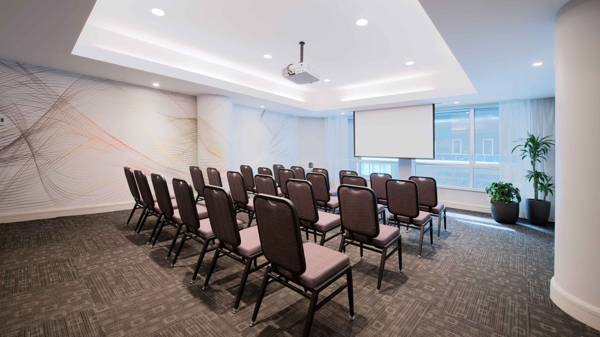 Theatre set-up with a projector screen and carpeted floors in Salon Drummond at Warwick Hotels and Resorts