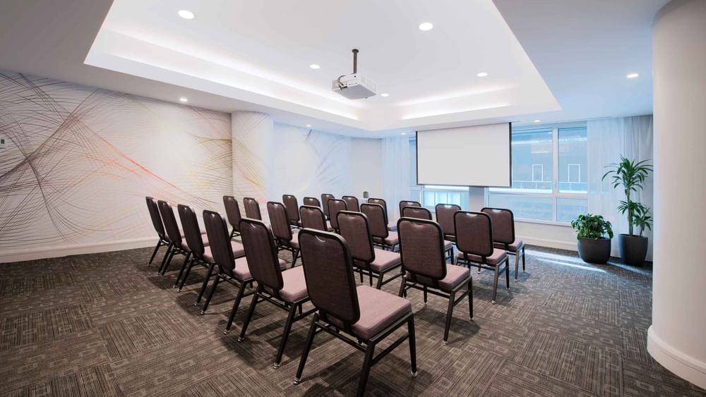 Theatre set-up with a projector screen and carpeted floors in Salon Drummond at Warwick Le Crystal Montreal