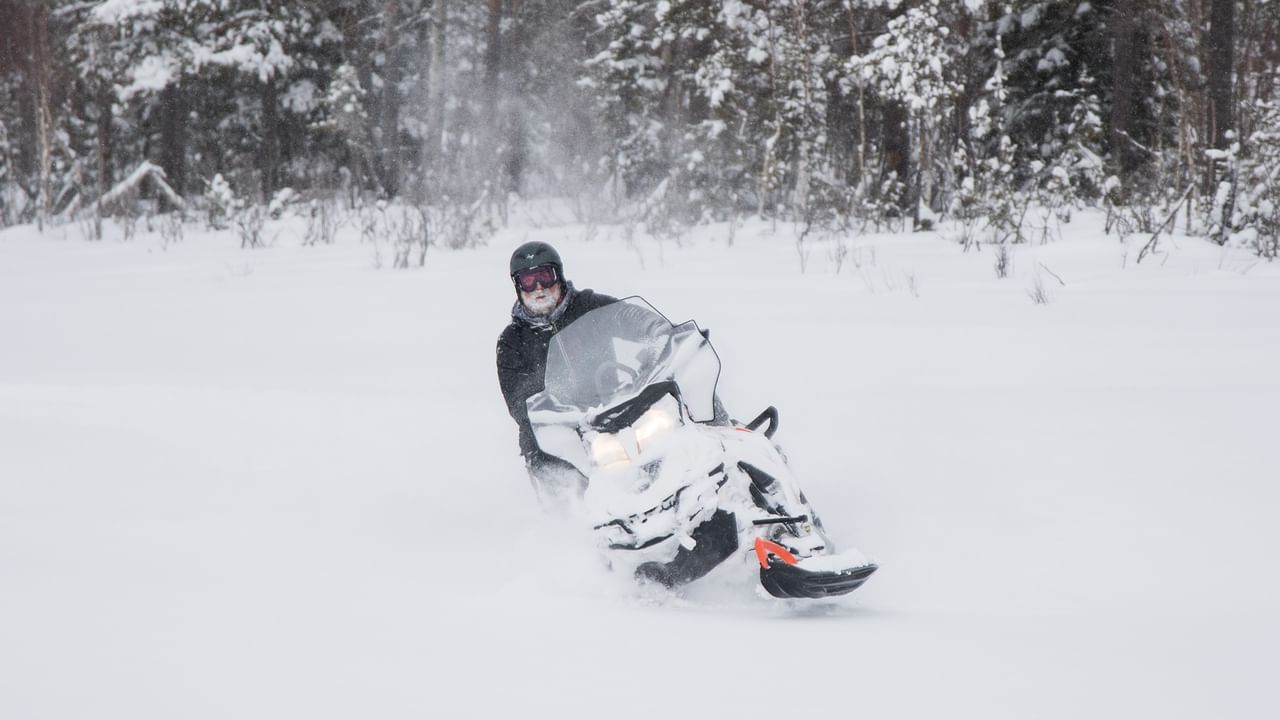 Person riding a snowmobile in a snowy landscape.