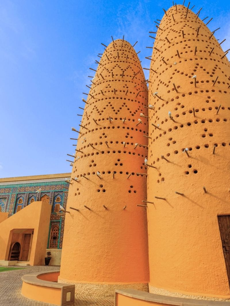 Katara by a colorful tiled wall under a bright sky near the cultural area near Warwick Doha Hotel