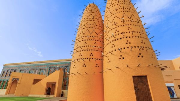 Katara by a colorful tiled wall under a bright sky near the cultural area near Warwick Doha Hotel