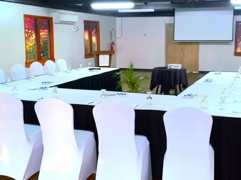 Professional meeting room with a U-shaped table setup and a projector screen at Warwick Hotels and Resorts