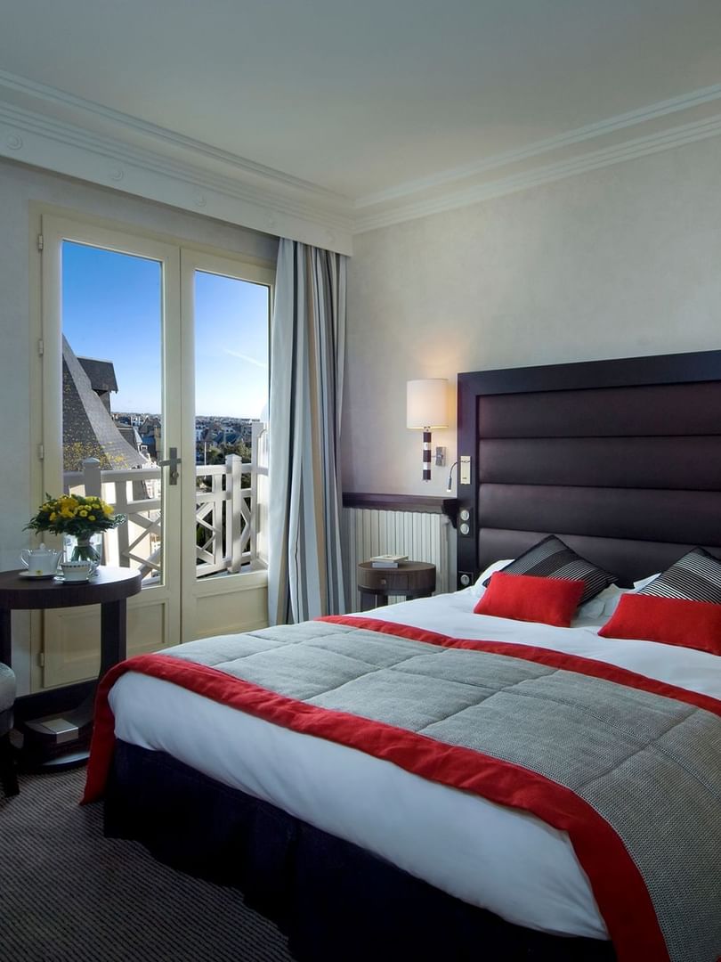 Double bed and seating area with city view in Transat Emeraude at Le Grand Hôtel des Thermes
