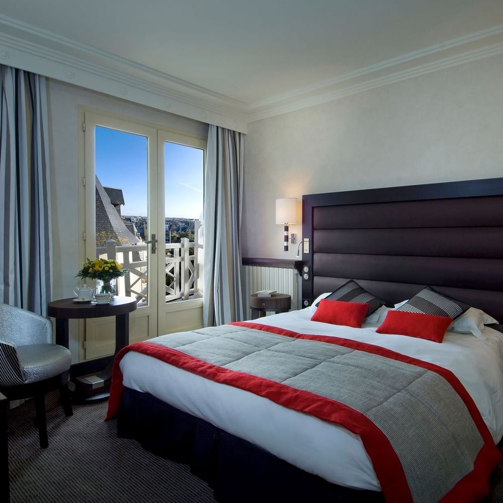 Double bed and seating area with city view in Transat Emeraude at Le Grand Hôtel des Thermes