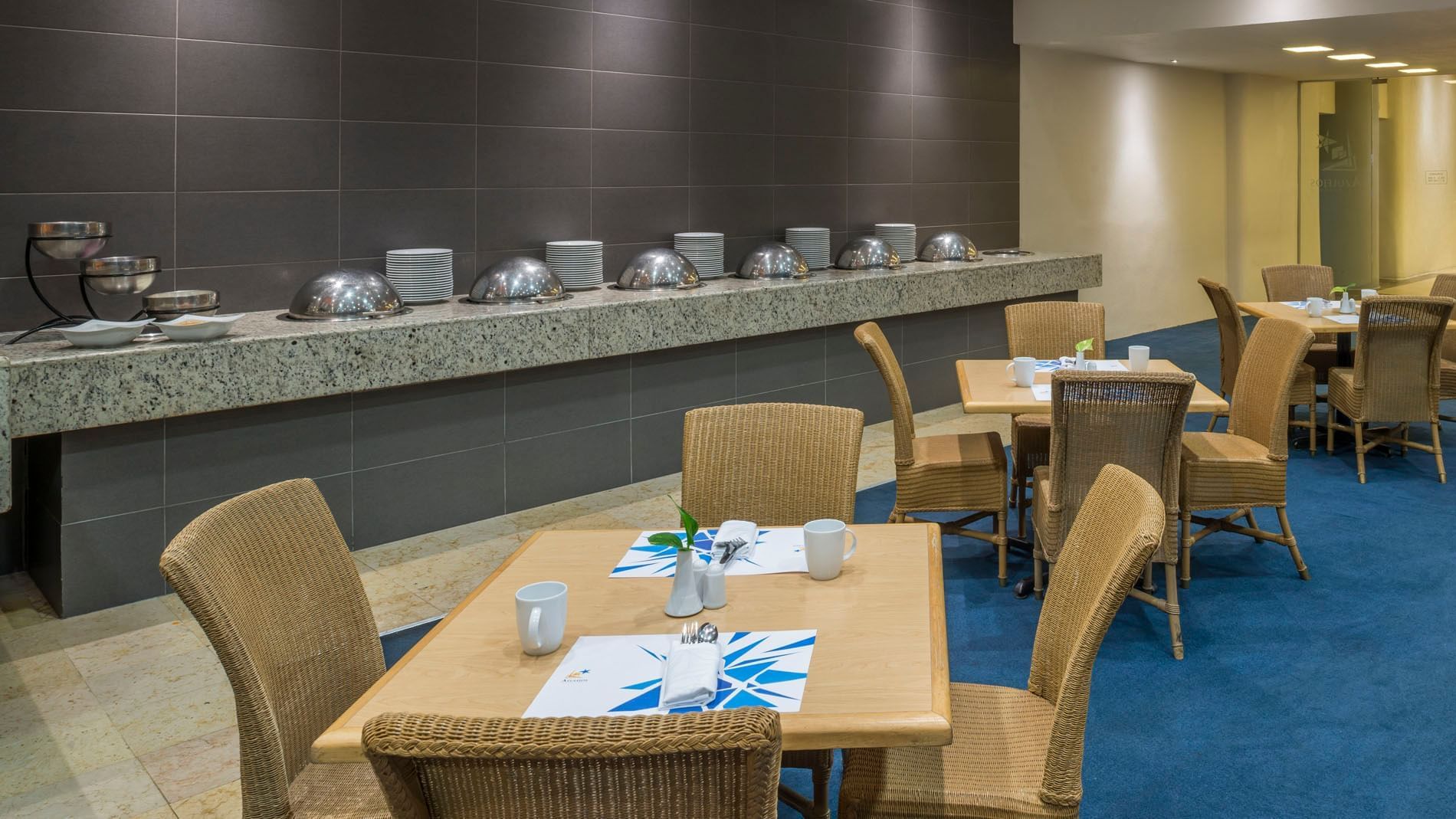 Azulejos restaurant dining area with set dining tables and wicker chairs nearby at Real Inn Nuevo Laredo