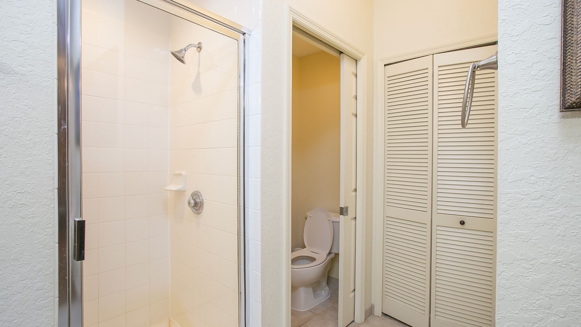 A bathroom with a shower, toilet, and closet.