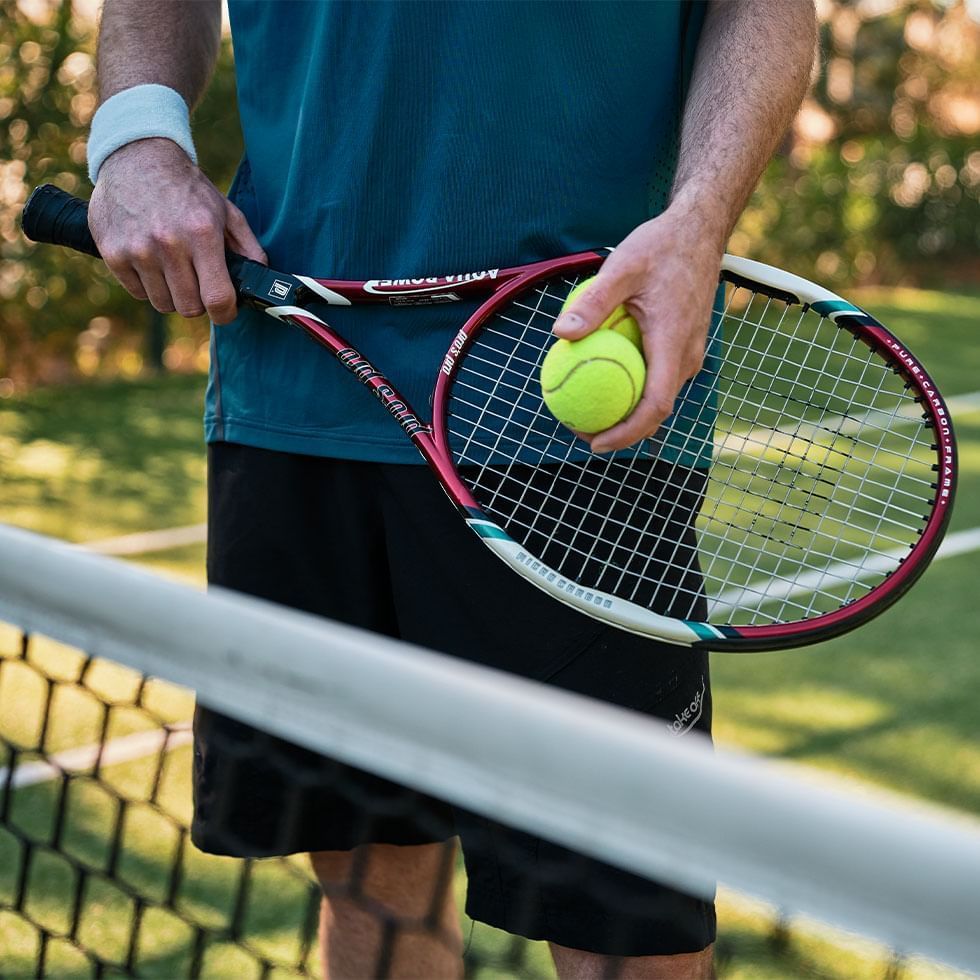 Tennis player holding a racket & a ball at Falkensteiner Hotels