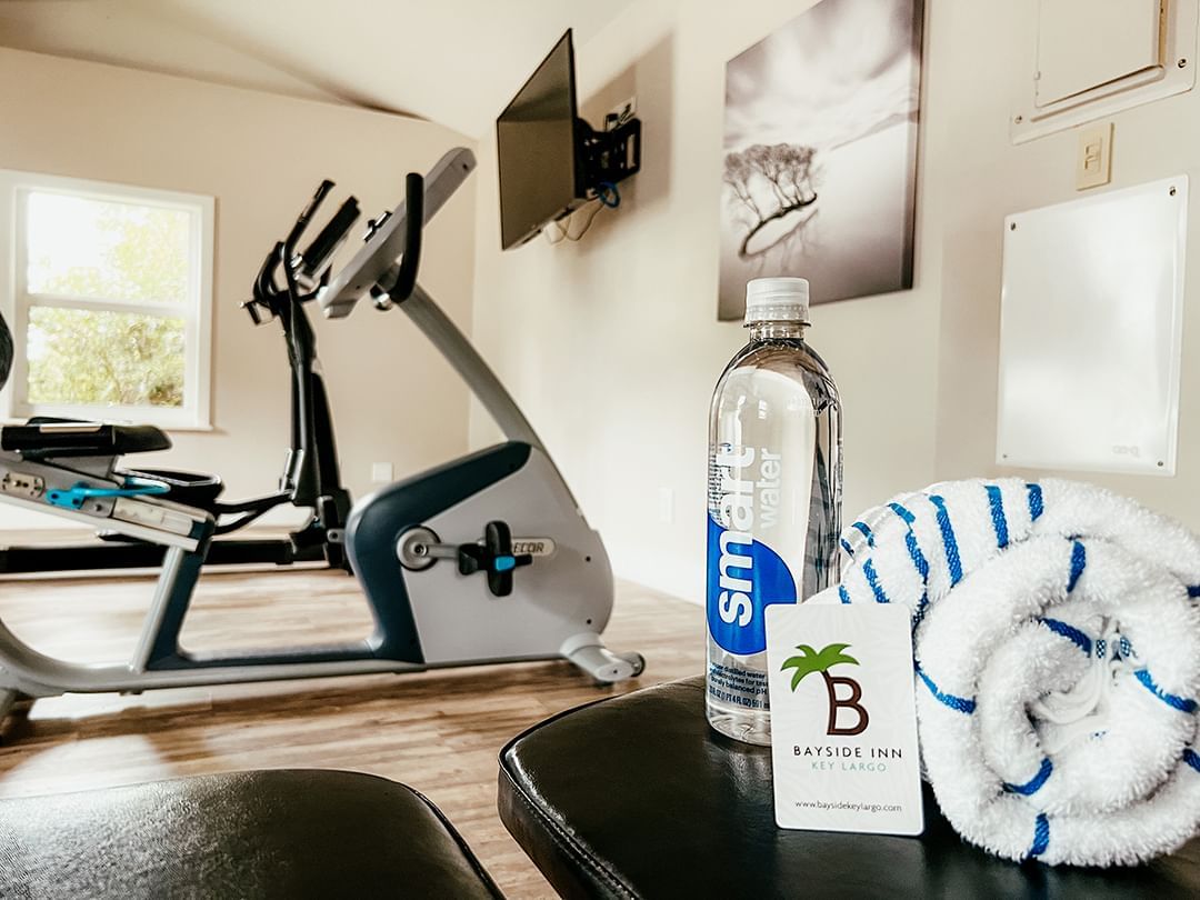Fitness room with an exercise bike, water bottle, towel, and Bayside Inn card on a table.