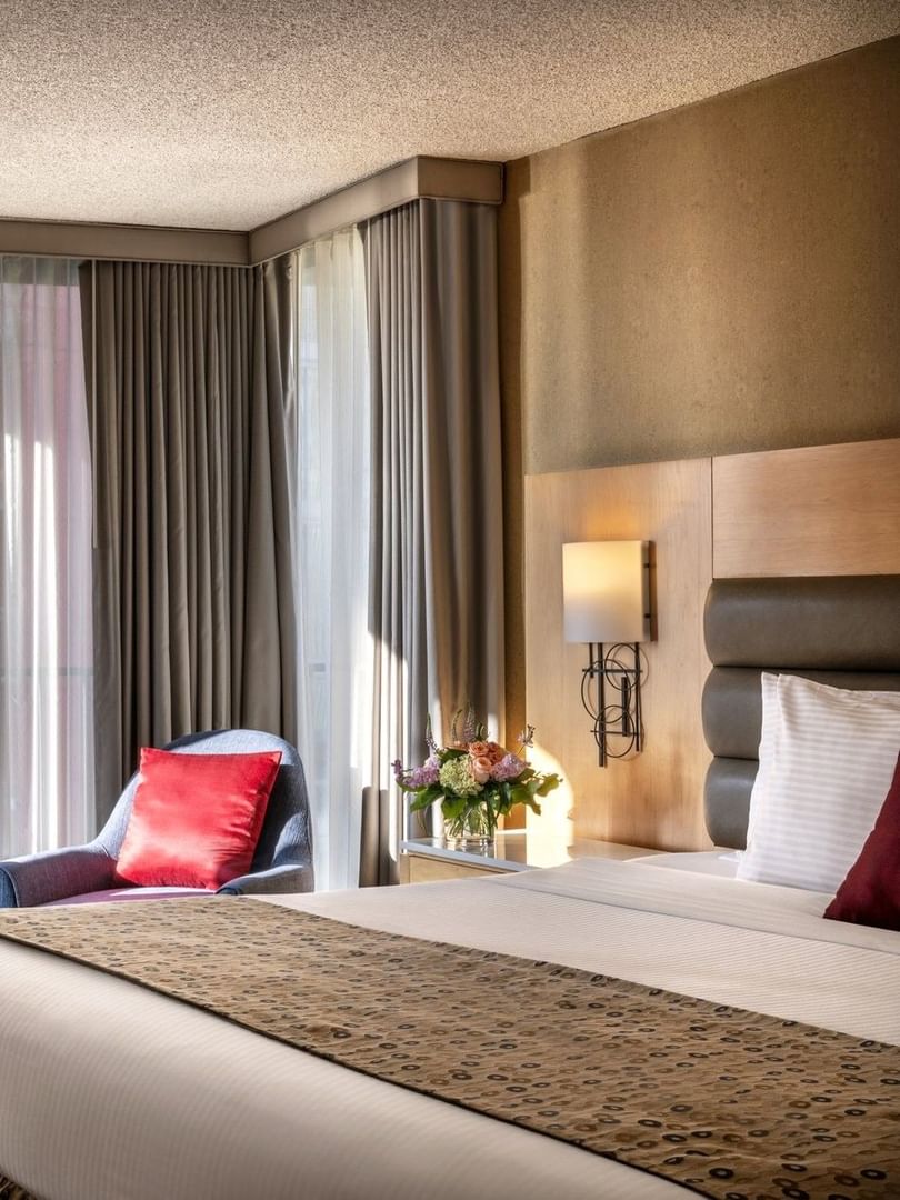 Blue armchair with a red pillow by floor-to-ceiling windows in Deluxe Rooms at Warwick Seattle