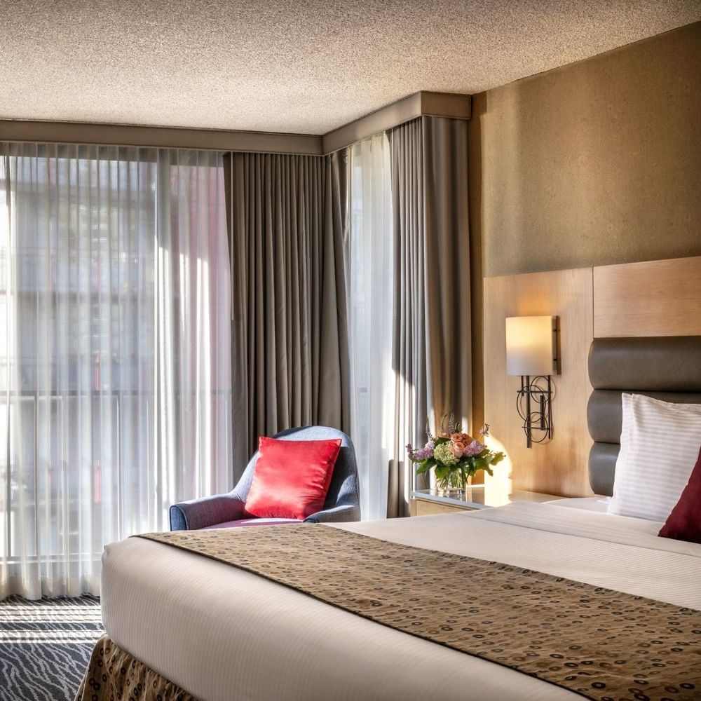 Blue armchair with a red pillow by floor-to-ceiling windows in Deluxe Rooms at Warwick Seattle