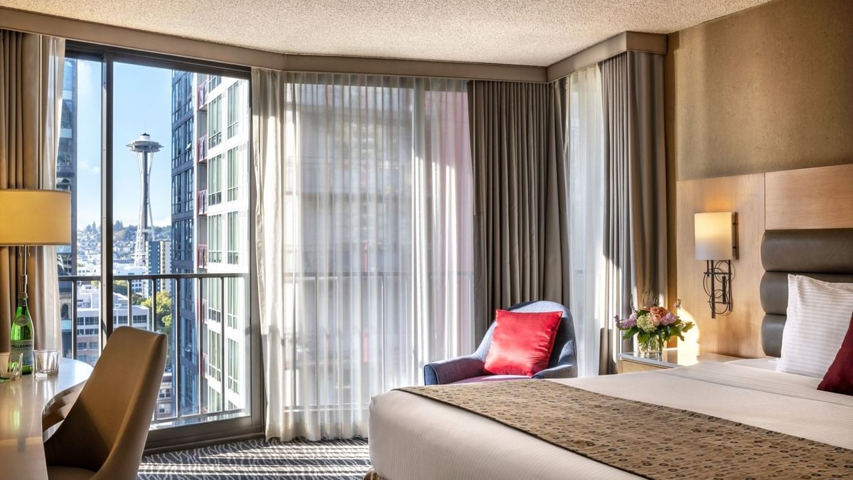 Blue armchair with a red pillow by floor-to-ceiling windows in Deluxe Rooms at Warwick Seattle