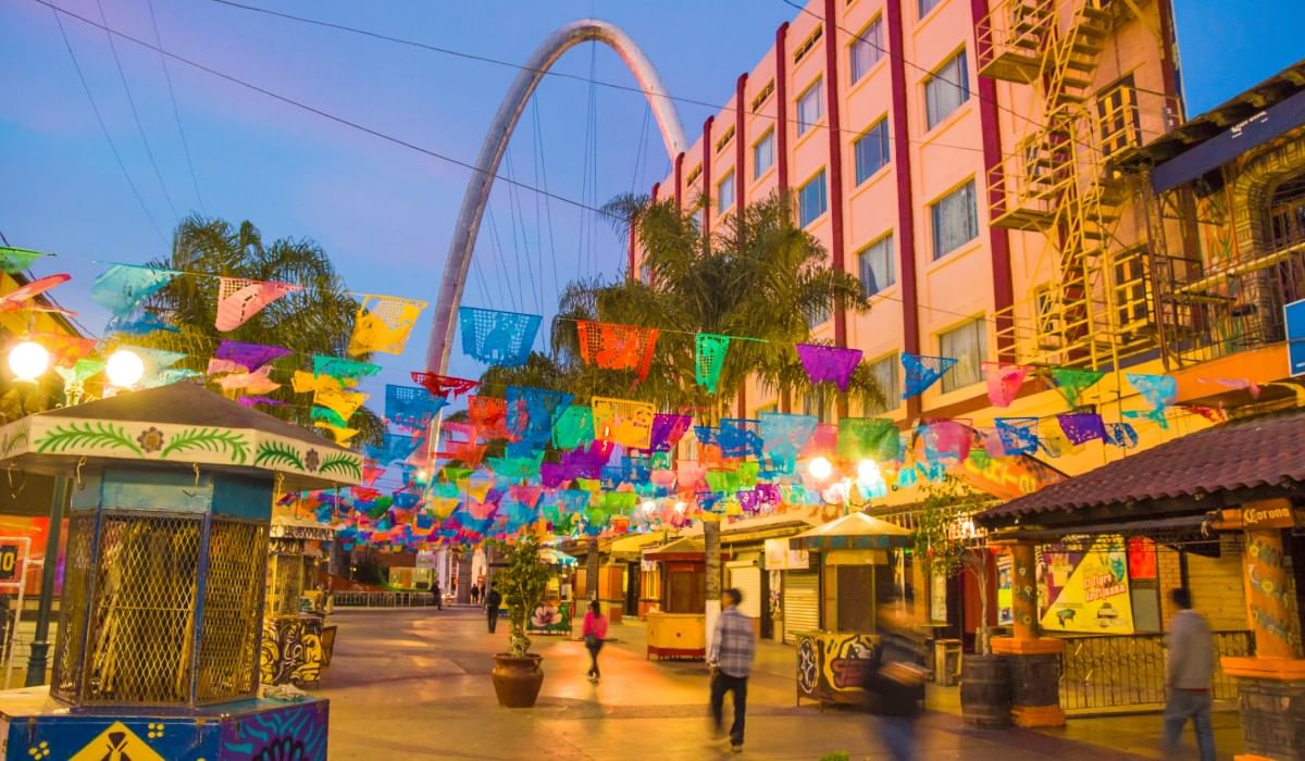Banderas coloridas colgando sobre una calle cerca del Arco de Tijuana y Camino Real Hotels