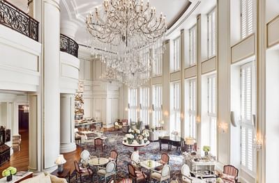 Dining area with a grand chandelier, ornate furniture, and large windows in Park Lounge at Park Hyatt Saigon