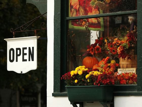 A window box with autumn flowers and a pumpkin, with an 'OPEN' sign, near The Pointe at Castle Hill