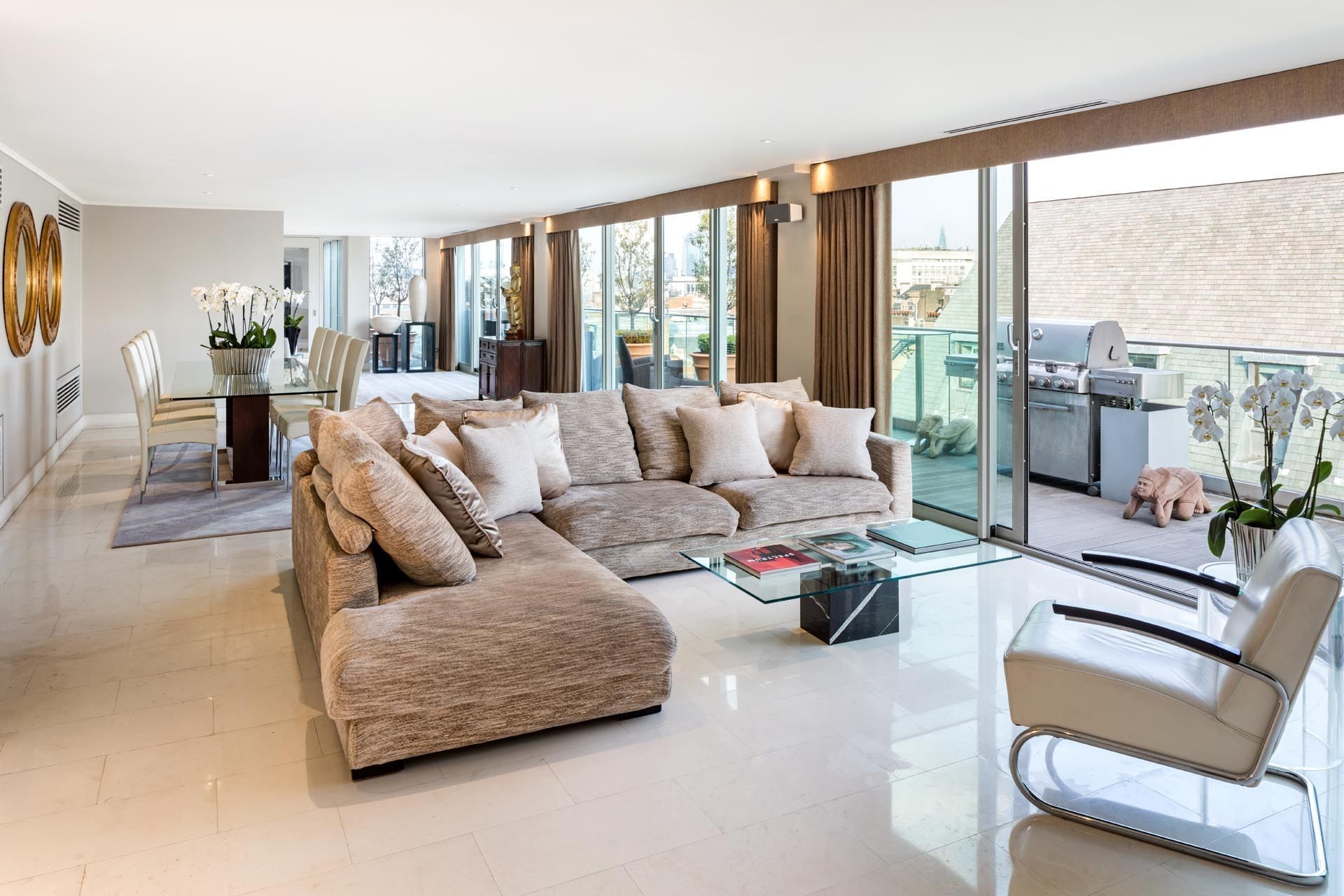 Penthouse Suite lounge area with a large L-shaped sofa and a terrace offering city views at The May Fair Hotel