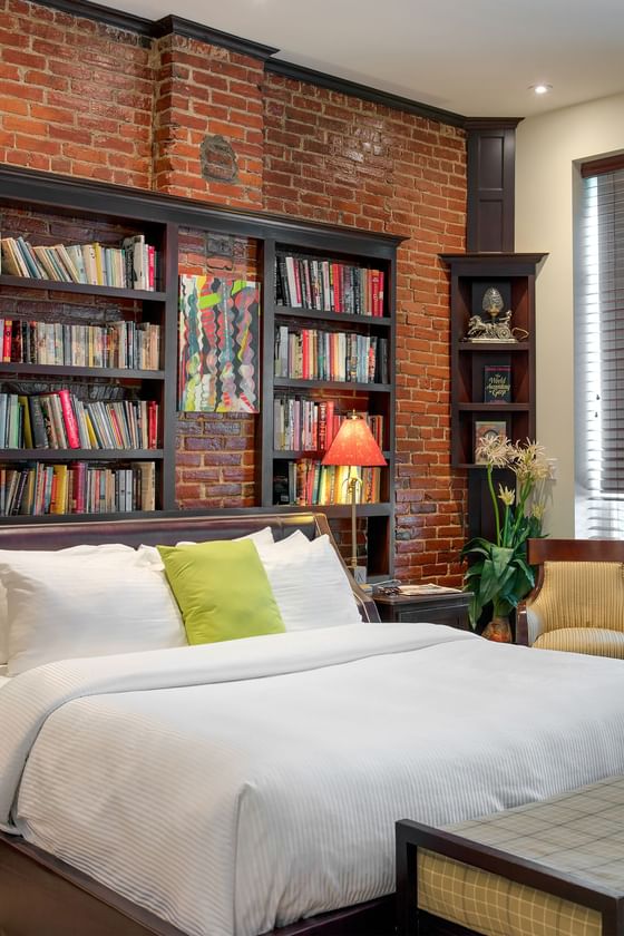 king bed with book collection in behind and bench at foot of bed