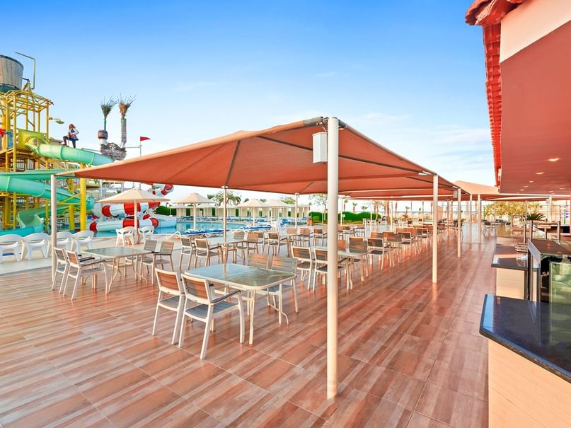 Outdoor food court area with tables and chairs under sunshades at Pickalbatros Aqua Blu Resort in Red Sea Governorate.