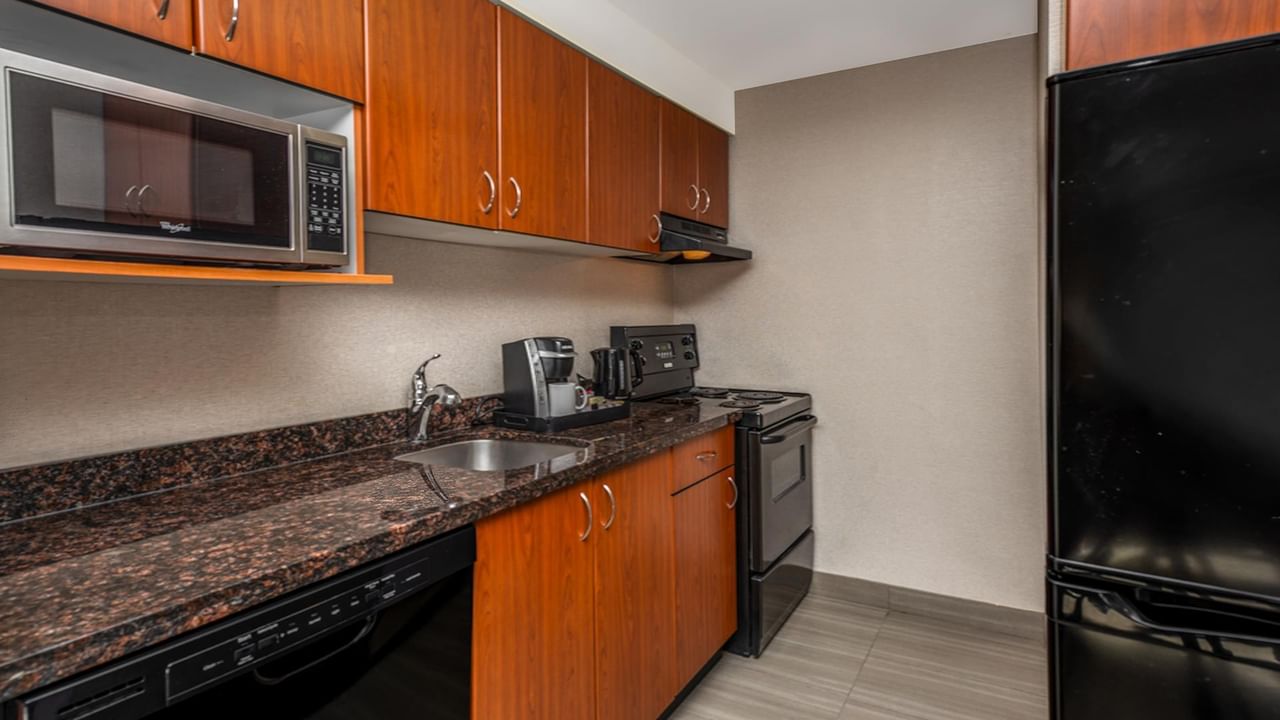 Hotel kitchen with granite countertops, wooden cabinets, and appliances.