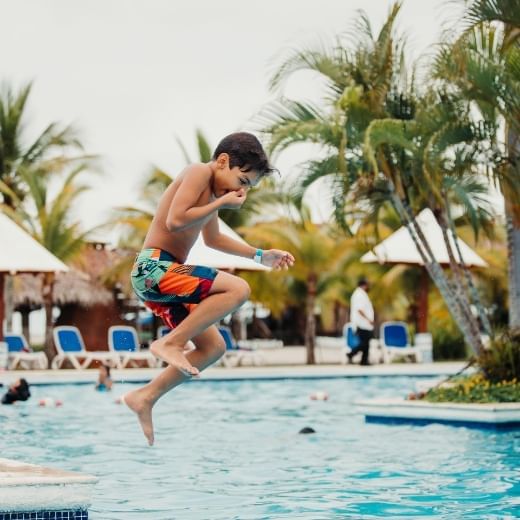 Boy jumping into the saltwater pool at Playa Blanca Beach Resort