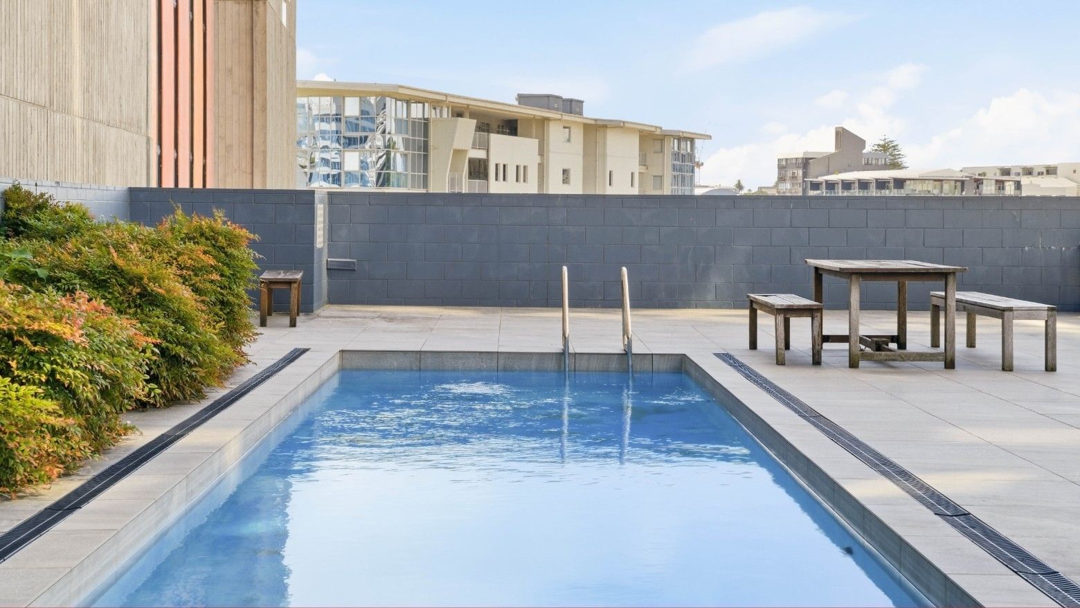 An outdoor pool with table and benches at Student Living Auckland - Beach.