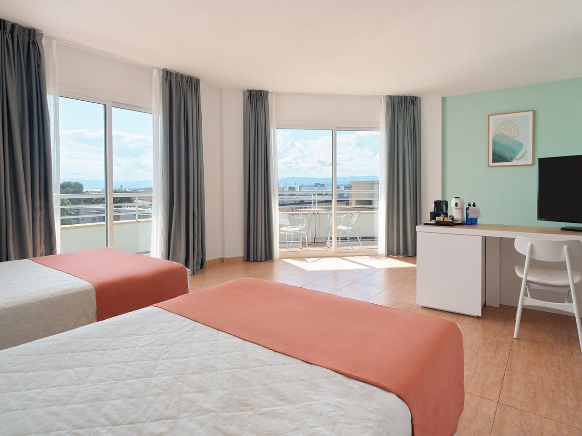 Junior Suite Rooms featuring two beds, wood flooring, and floor-to-ceiling doors open onto a balcony at Hotel Pirámide Salou