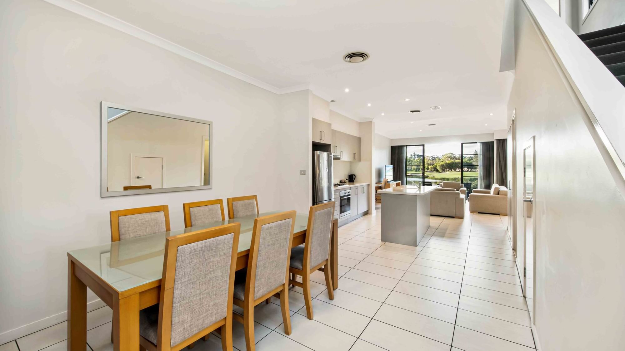 Three Bedroom Apartment dining area with table, leading to an open-plan kitchen and living area at Mercure Kooindah Waters