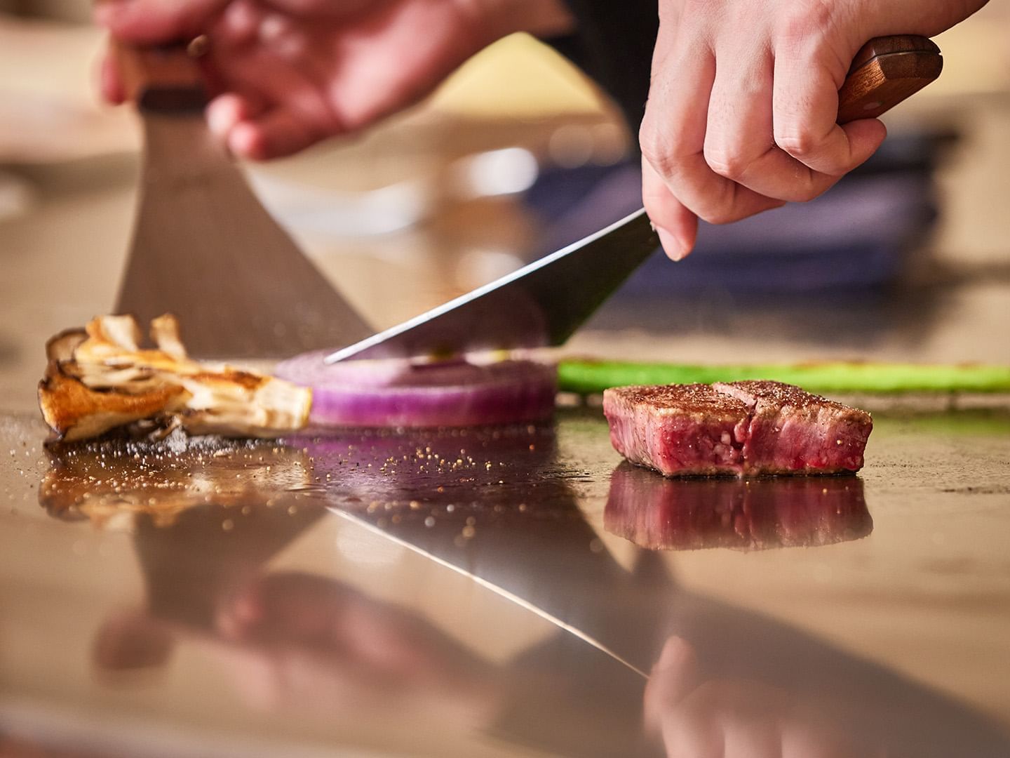 A person slicing a steak on a wooden cutting board at Grand Park  Otaru