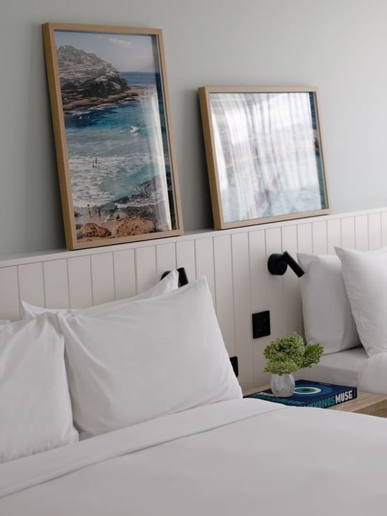 Atrium Twin at Elysium Manly under framed ocean photography by a wooden nightstand with greenery and a coffee table book