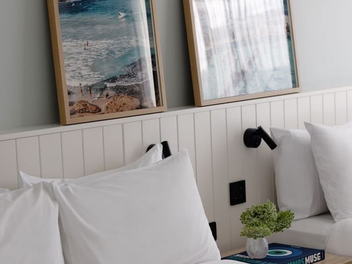 Atrium Twin at Elysium Manly under framed ocean photography by a wooden nightstand with greenery and a coffee table book