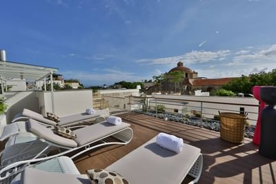 Rooftop terrace with lounge chairs overlooking a domed building and greenery at Billini Hotel Historic Luxury