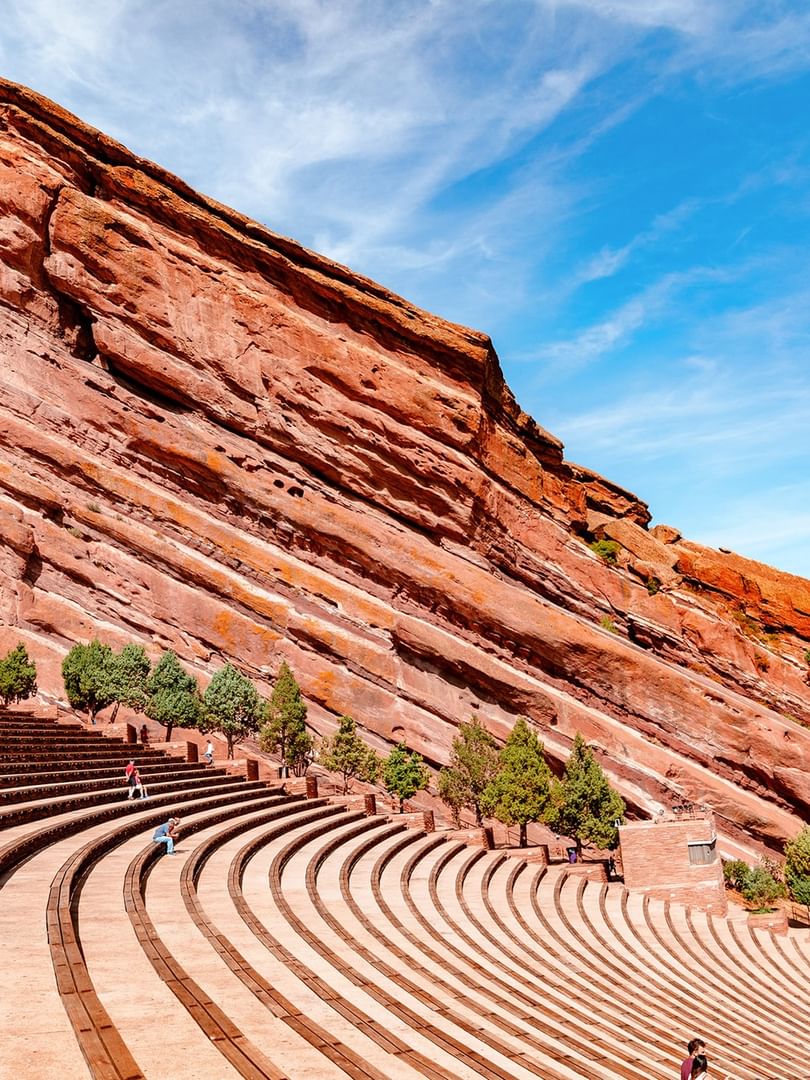 Red Rocks Park by a massive red rock formation under a bright blue sky near Warwick Denver