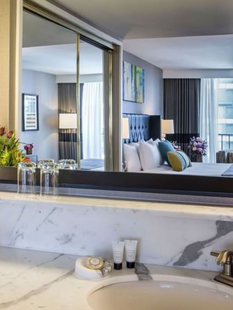 Elegant bathroom with a marble countertop, mirror, and floral arrangement in the Emerald Suite at Warwick Seattle