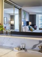 Elegant bathroom with a marble countertop, mirror, and floral arrangement in the Emerald Suite at Warwick Seattle
