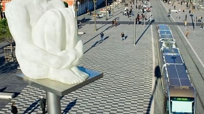 Modern tram passing by a public square with a white statue sculpture in the city near Splendid Hotel & Spa Nice