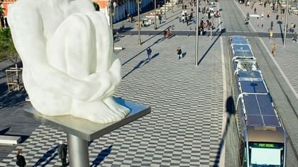 Modern tram passing by a public square with a white statue sculpture in the city near Splendid Hotel & Spa Nice