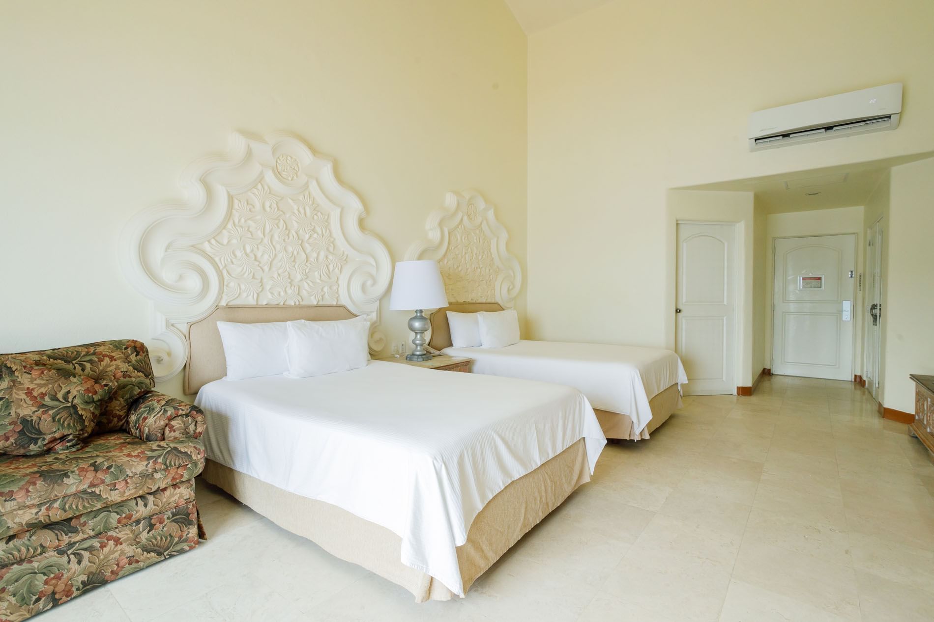 2 Double Master Suite with decorative headboards and a floral patterned armchair at Quinta Real Acapulco