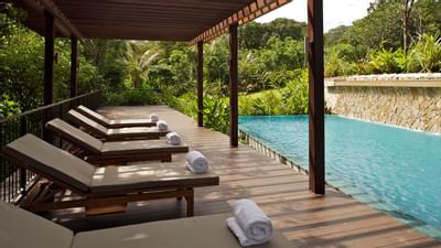 Lounge chairs on the deck by the pool at Amara Sanctuary Resort
