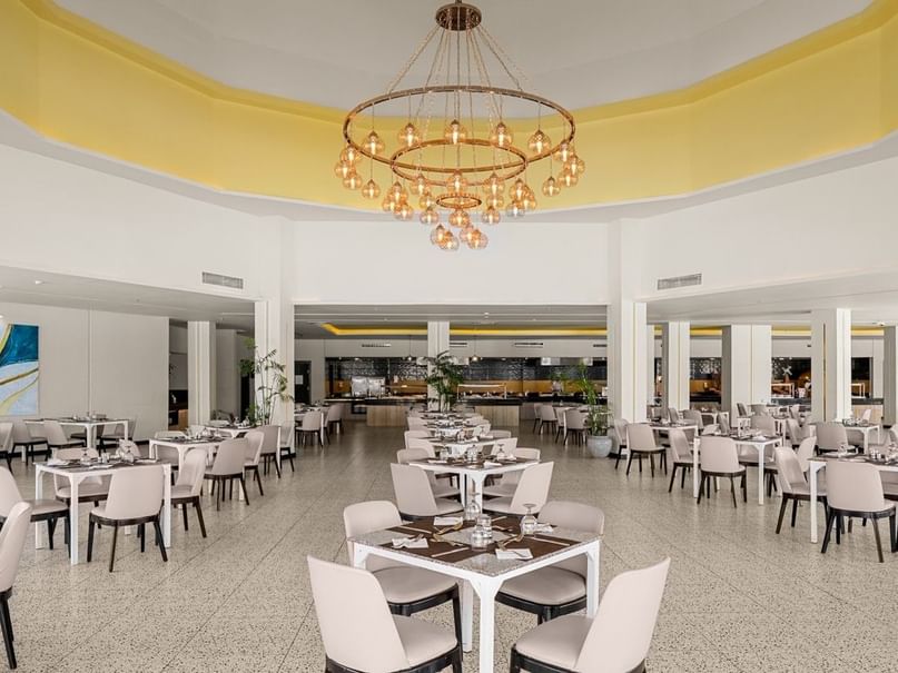 Elegant dining area with white tables and chairs under a grand chandelier at Neverland City Hurghada in Hurghada.