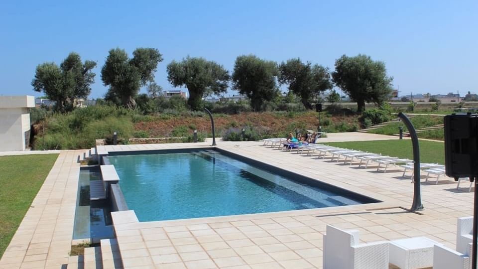 Outdoor pool & sunbed area on a sunny day at Originals Hotels