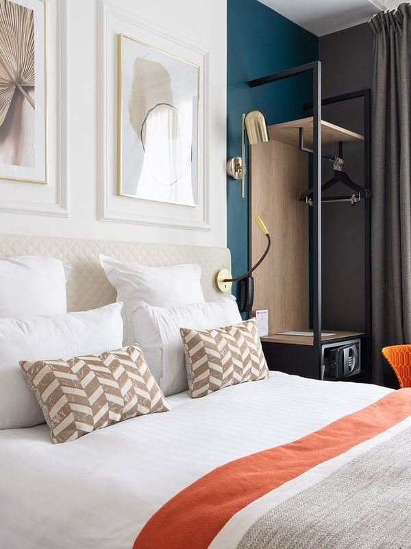 Stylish room with a plush bed, decorative pillows, modern art, and a cozy window-side chair at Oceania Hotel D'Anjou Angers