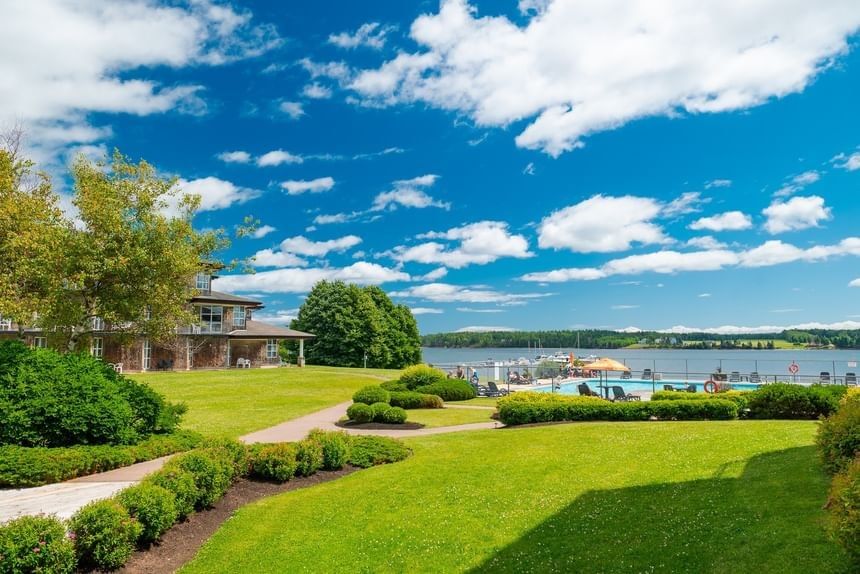 Beautiful outdoor swimming pool area with green lawn overlooking the sunny riverfront resort at Rodd Brudenell River