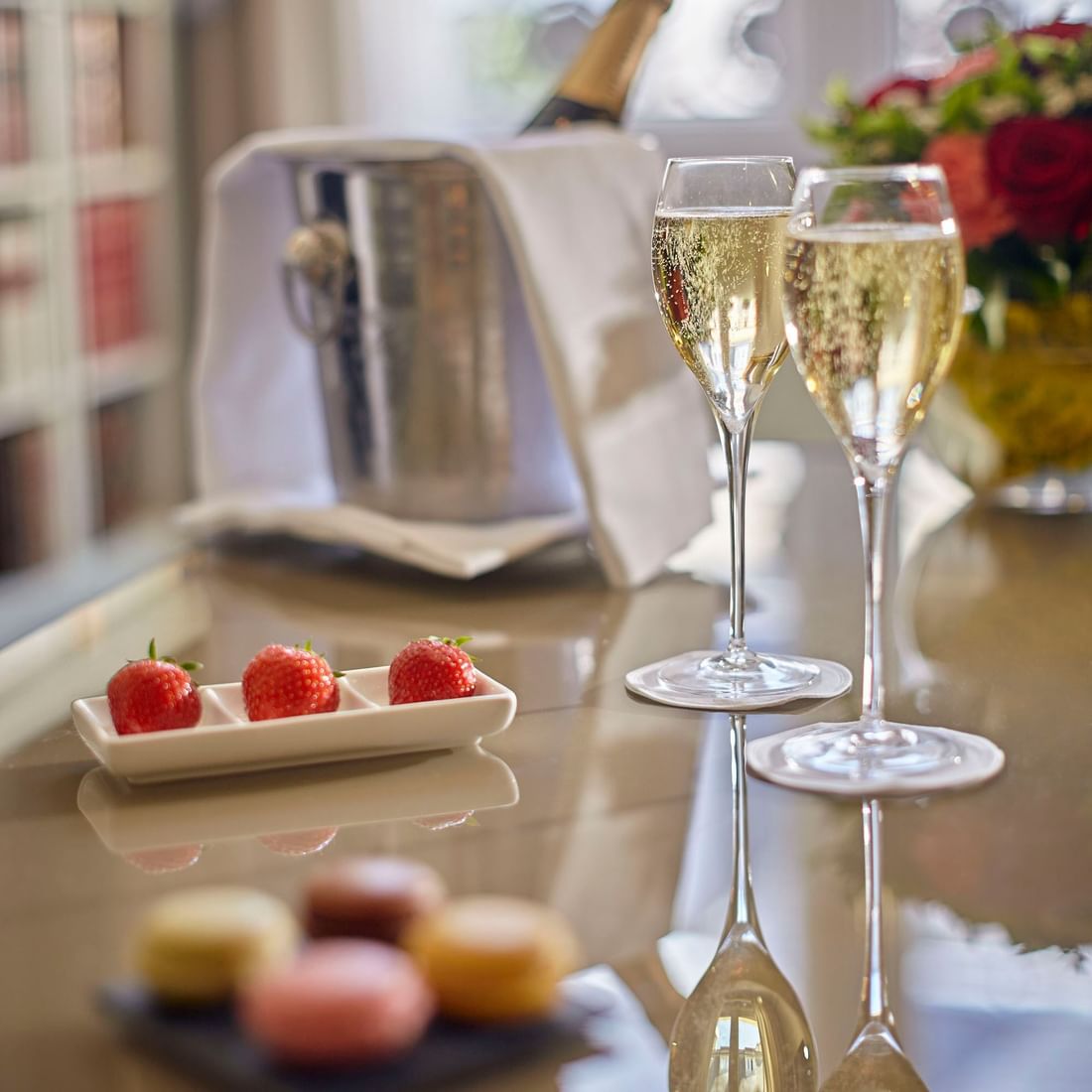 Two champagne glasses, strawberries, macarons, and a chilled bottle of champagne at Warwick Corporate