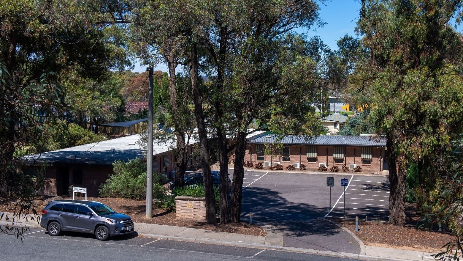 Car parked in front of La Trobe University - Orde House surrounded by trees.