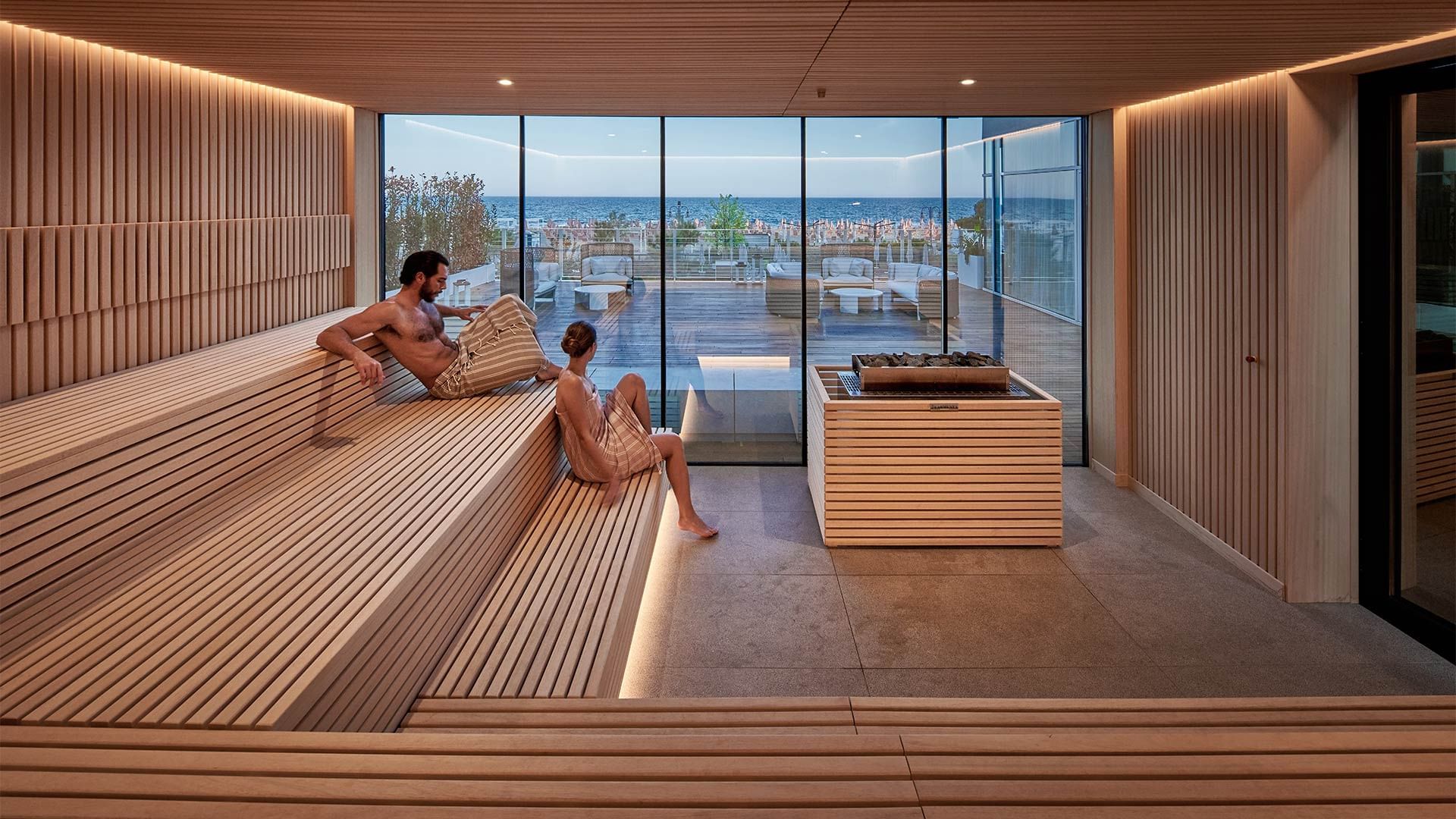 Two people on benches in sauna room of Acquapura Blue Horizon Spa at Falkensteiner Hotel & Spa Jesolo