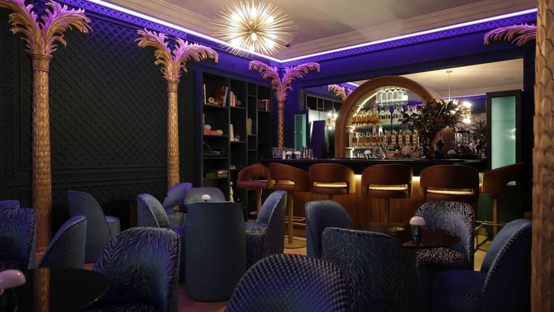بار فاخر بإضاءة بنفسجية وأعمدة ذهبية وكراسي مخملية زرقاء في Warwick Palm Beach Beirut Beyrouth