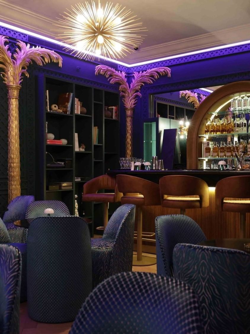 Blue seating by the bar counter with liquor shelves at The Bar in Warwick Palm Beach Hotel