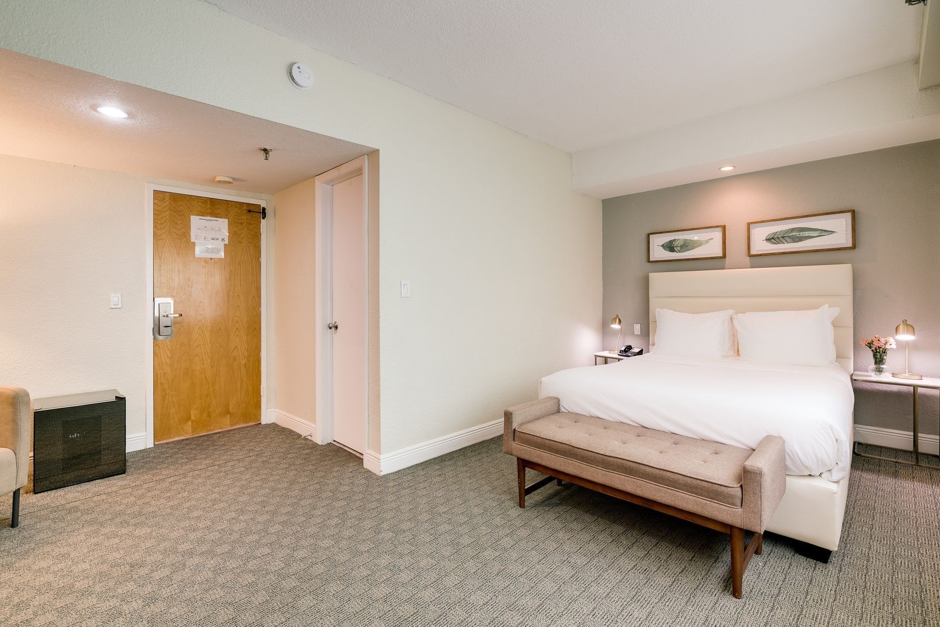 A hotel room with a bed, bench, and nightstands
