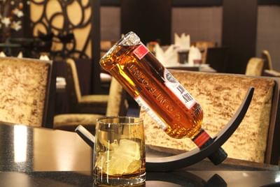 Bottle of alcohol and a glass with Ice cubes at Amora Hotel