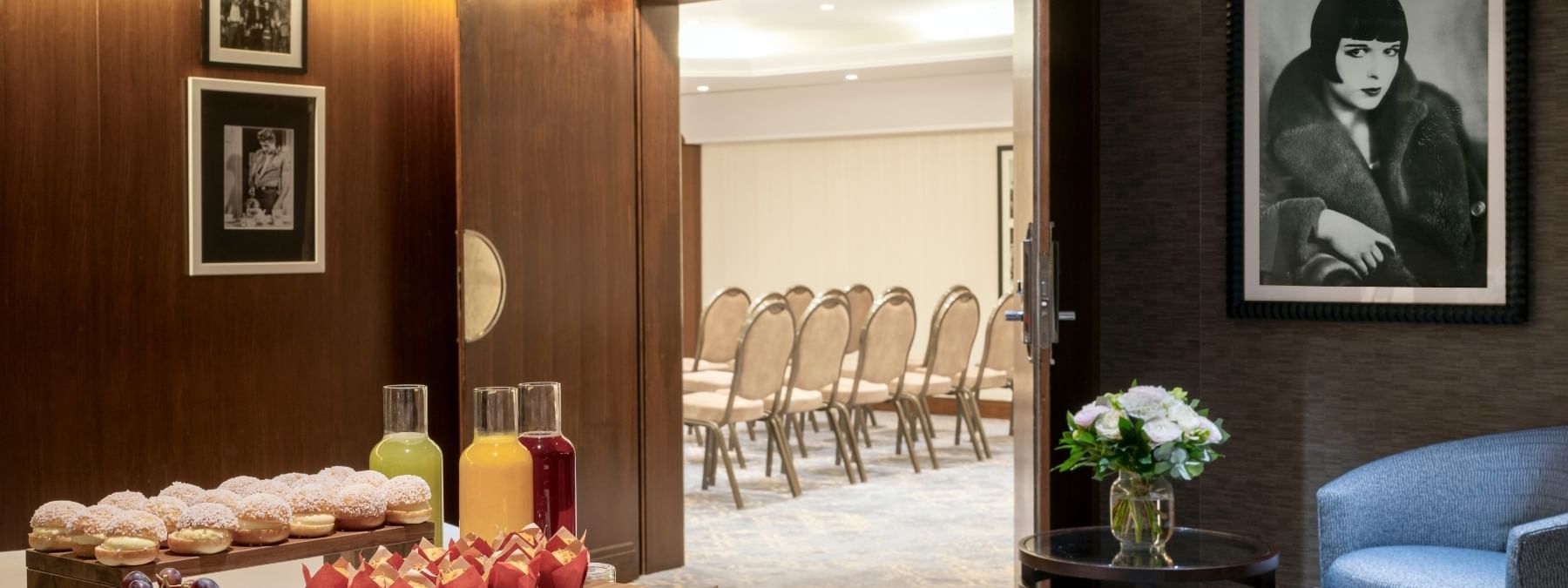 Juice carafes and pastries by a bowl of fruit under a portrait in Seminars & Banquets at Warwick Paris Champs Elysées