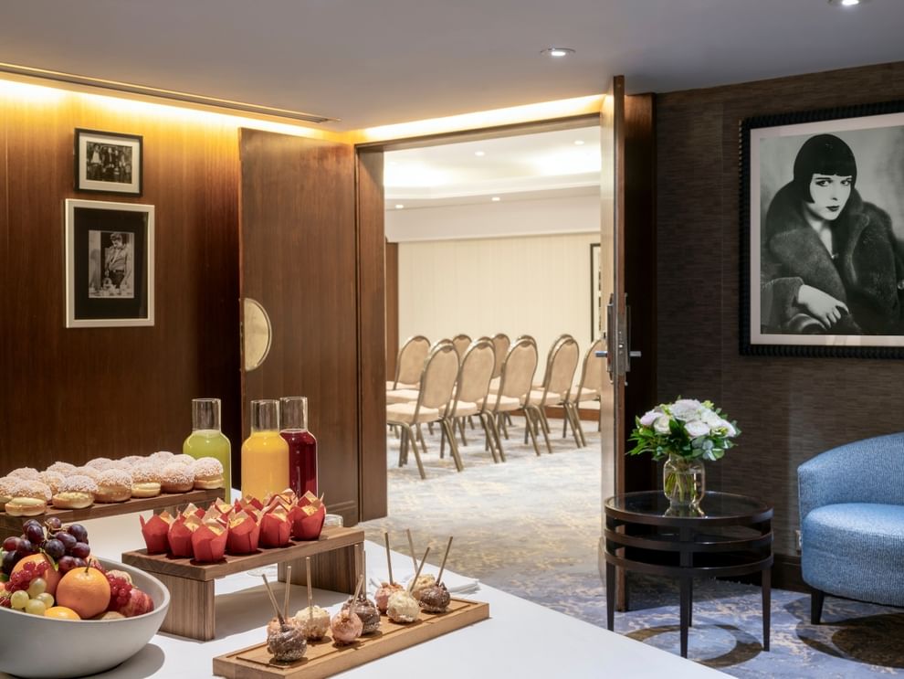 Juice carafes and pastries by a bowl of fruit under a portrait in Seminars & Banquets at Warwick Paris Champs Elysées